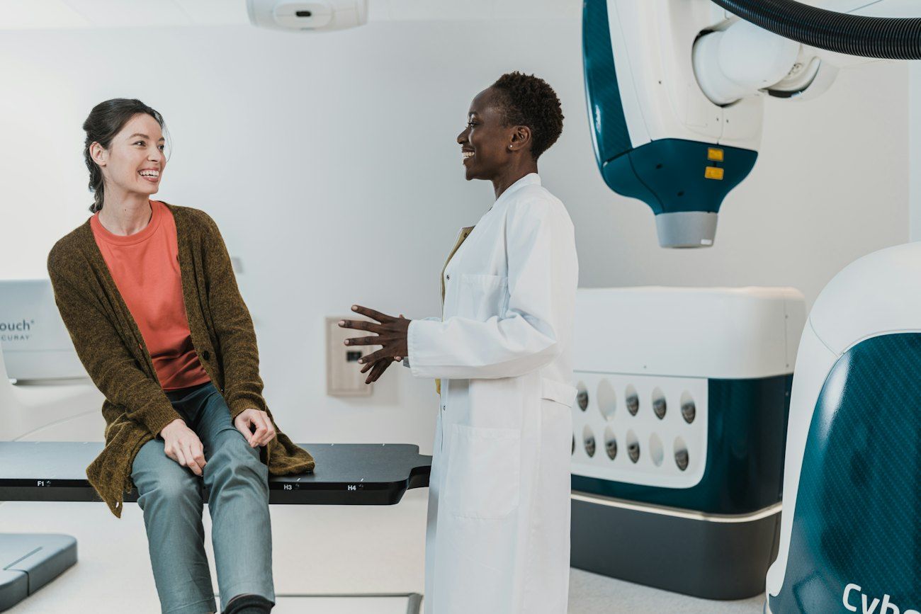 Een arts praat met een patiënte in een lichte kliniekkamer