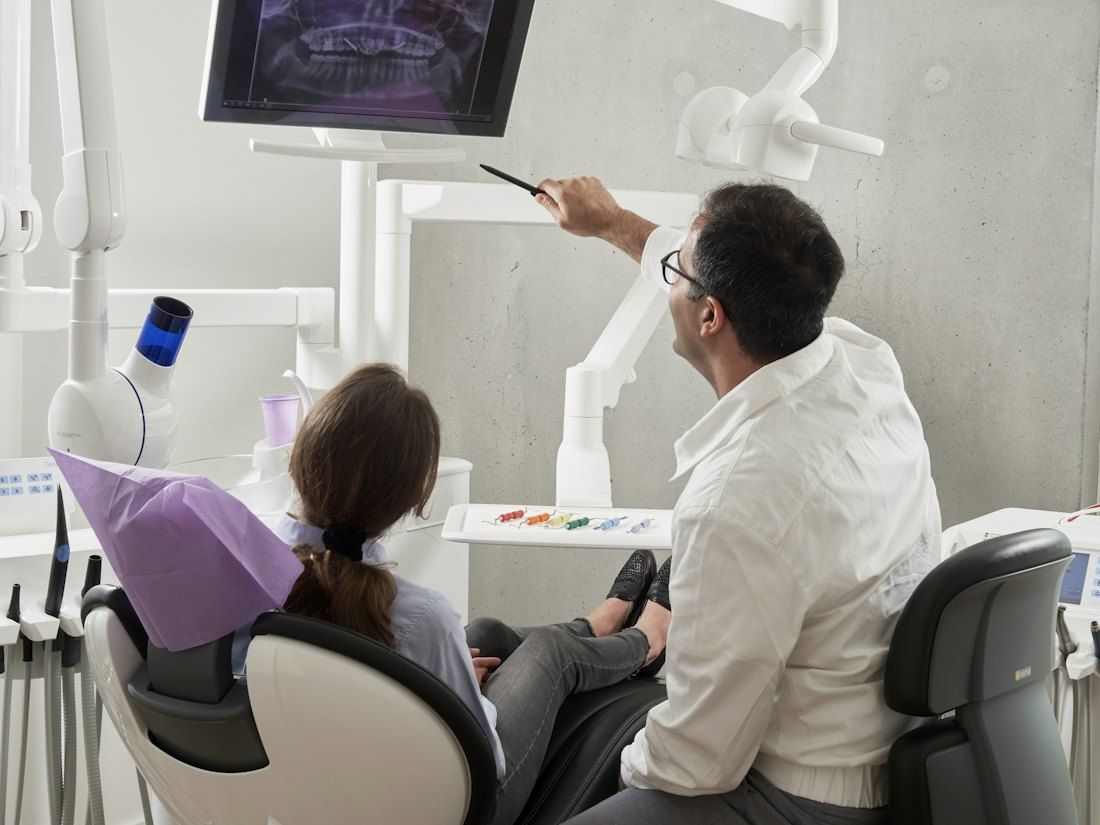 A dentist shows a patient her X-ray on a screen