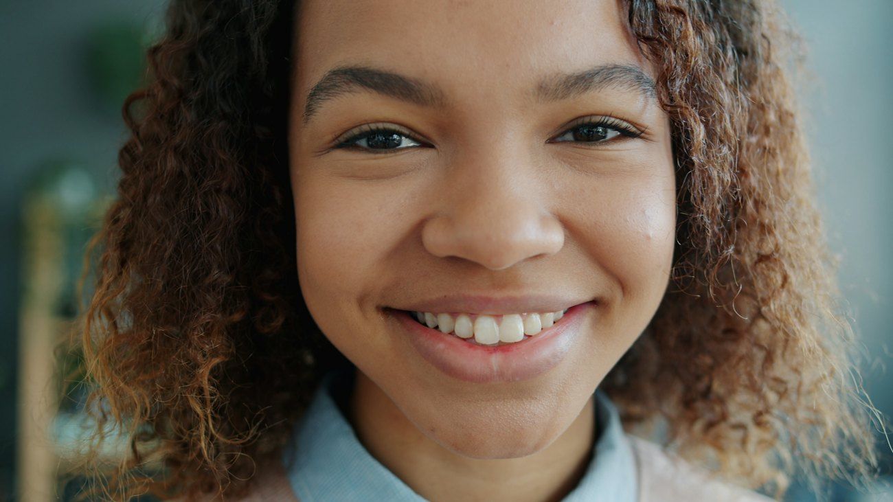 A young woman with curly hair smiles warmly